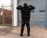 a man standing in front of a garage wearing a black hoodie